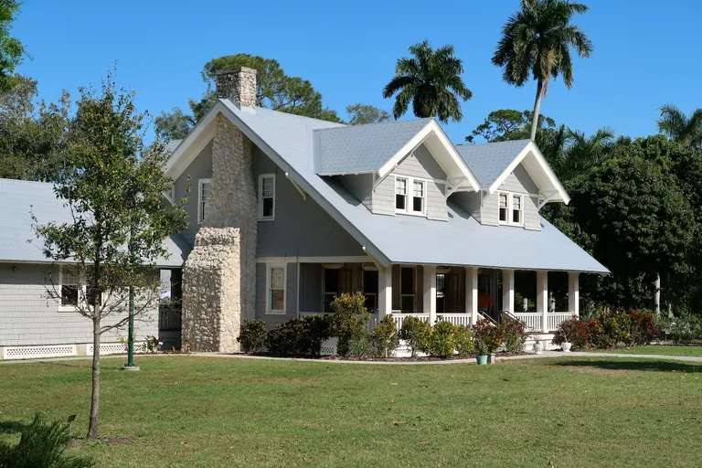 A bright two-story suburban home with a stone chimney and palm trees, the kind of home Noble evaluates every day